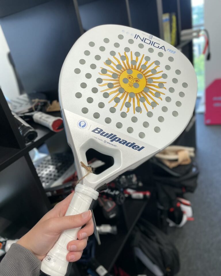 Roka tur baltu Bullpadel raketi, aiz muguras veikala plaukti — izmēģini pirms pirkšanas